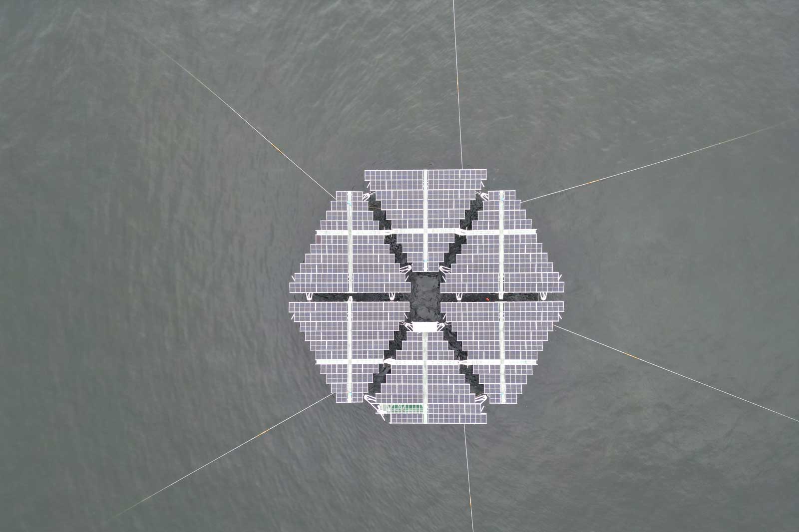 Eine schwimmende Solaranlage in einem hexagonalen Muster auf ruhigem Wasser.