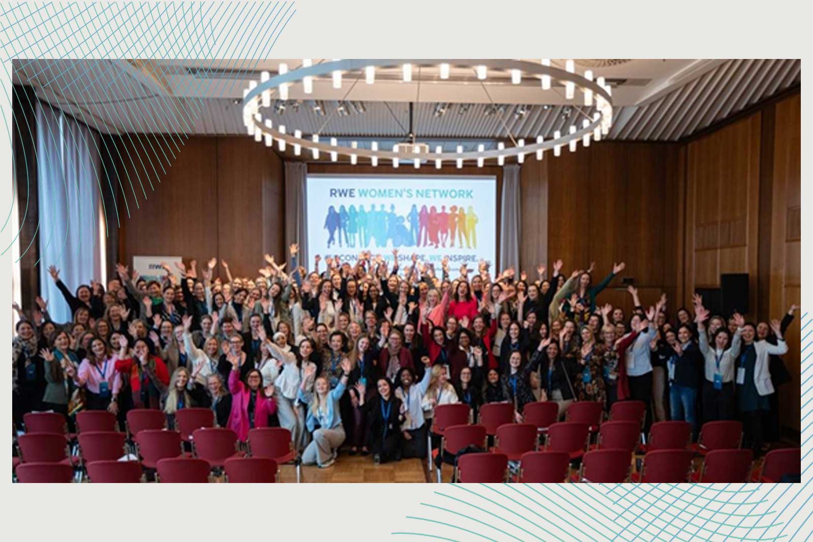 Eine große Gruppe von Menschen hebt die Hände in einem Raum mit einem Banner der RWE Frauen Netzwerk im Hintergrund.