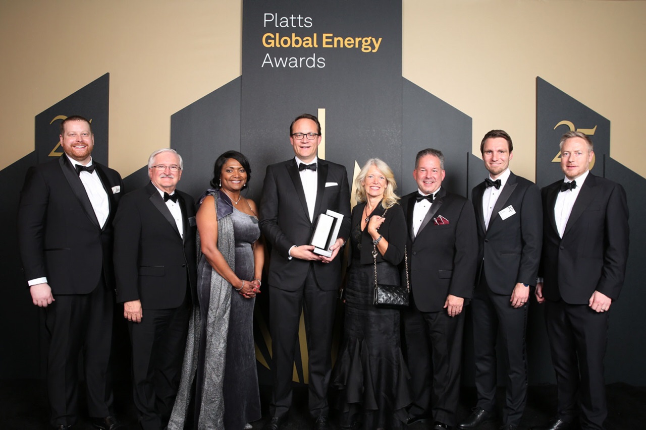 A group of individuals in formal attire poses at the Platts Global Energy Awards against a gold backdrop.