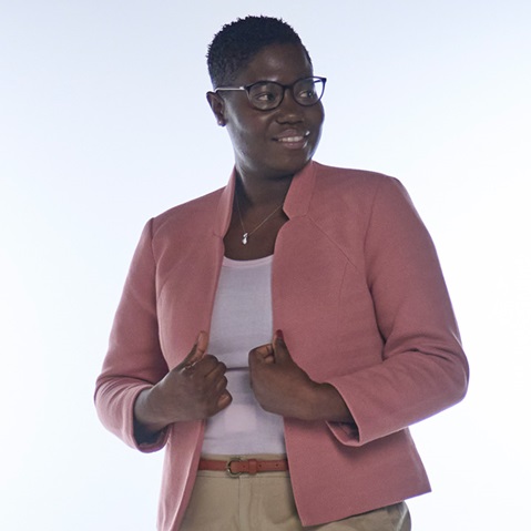 Eine Person trägt ein hellrosa Jackett über einem weissen Oberteil. Sie posiert mit beiden Händen an der Taille.