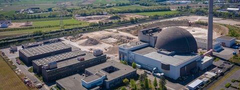 Aerial view of a nuclear power plant featuring a large domed structure and surrounding construction areas.