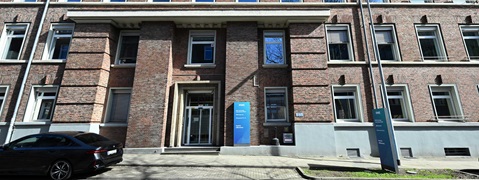 A modern brick office building with large windows and a glass entrance. A black car is parked in front.