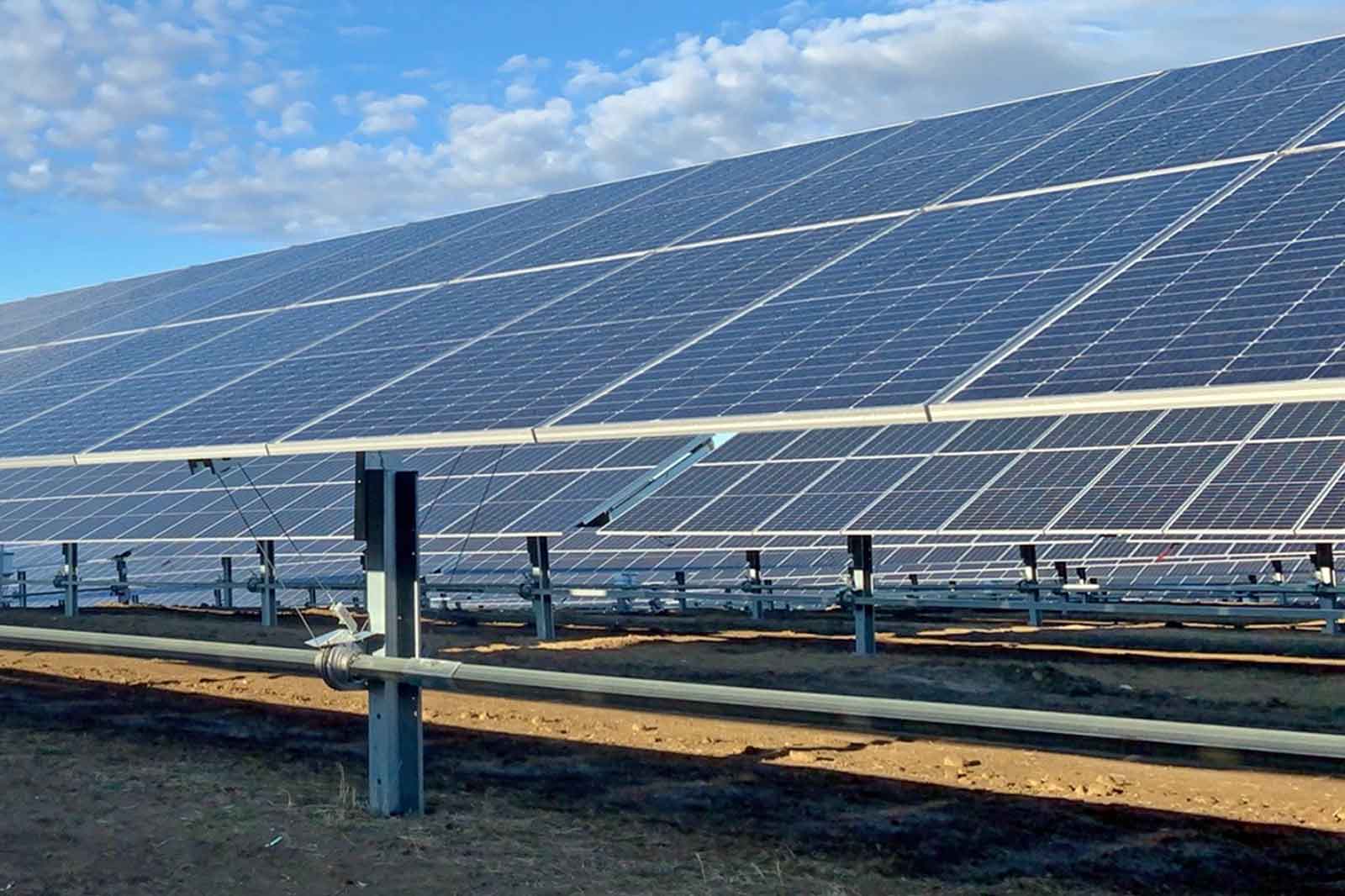 A solar farm featuring multiple solar panels installed on a gravel surface.