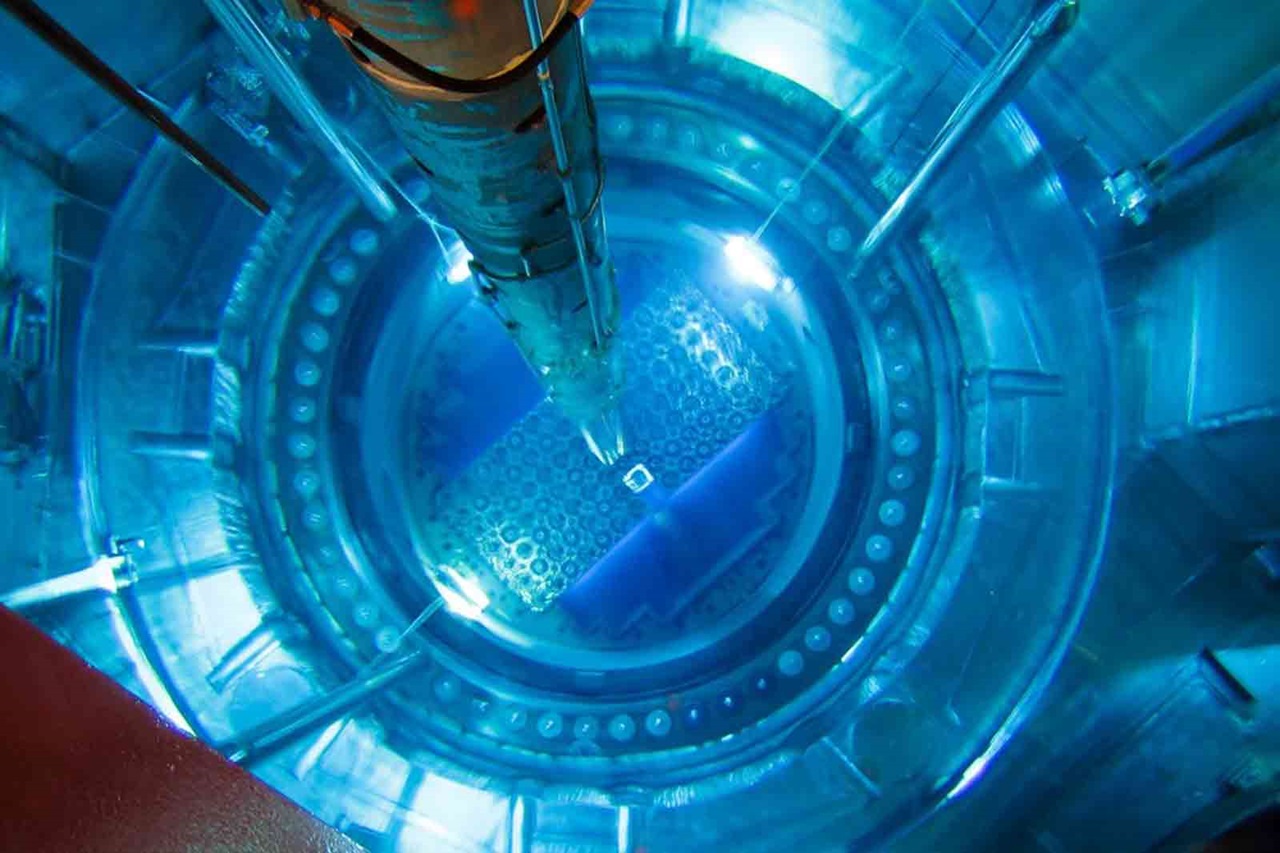 A top-down view of a nuclear reactor core with blue lighting, showcasing the fuel rods and hexagonal arrangements.