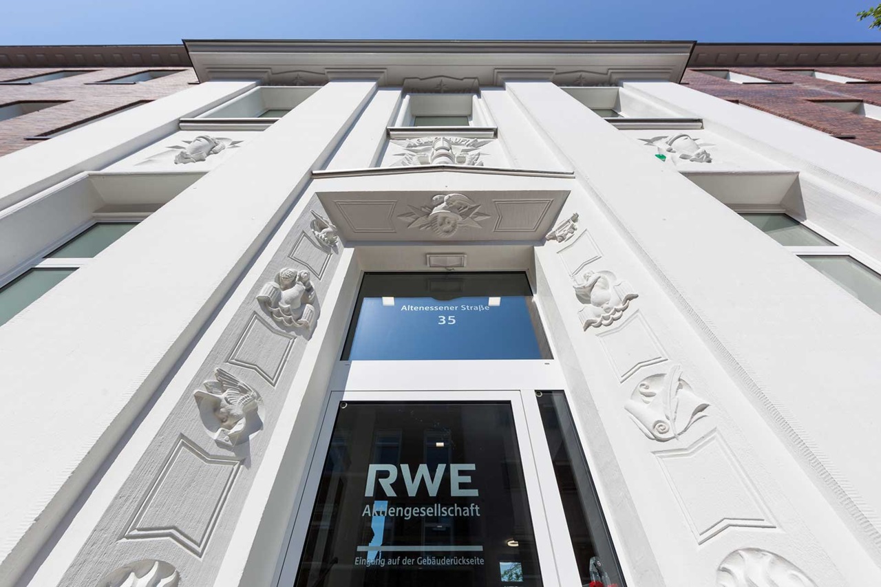 The image shows the entrance of a historic building with intricate reliefs and the lettering RWE.