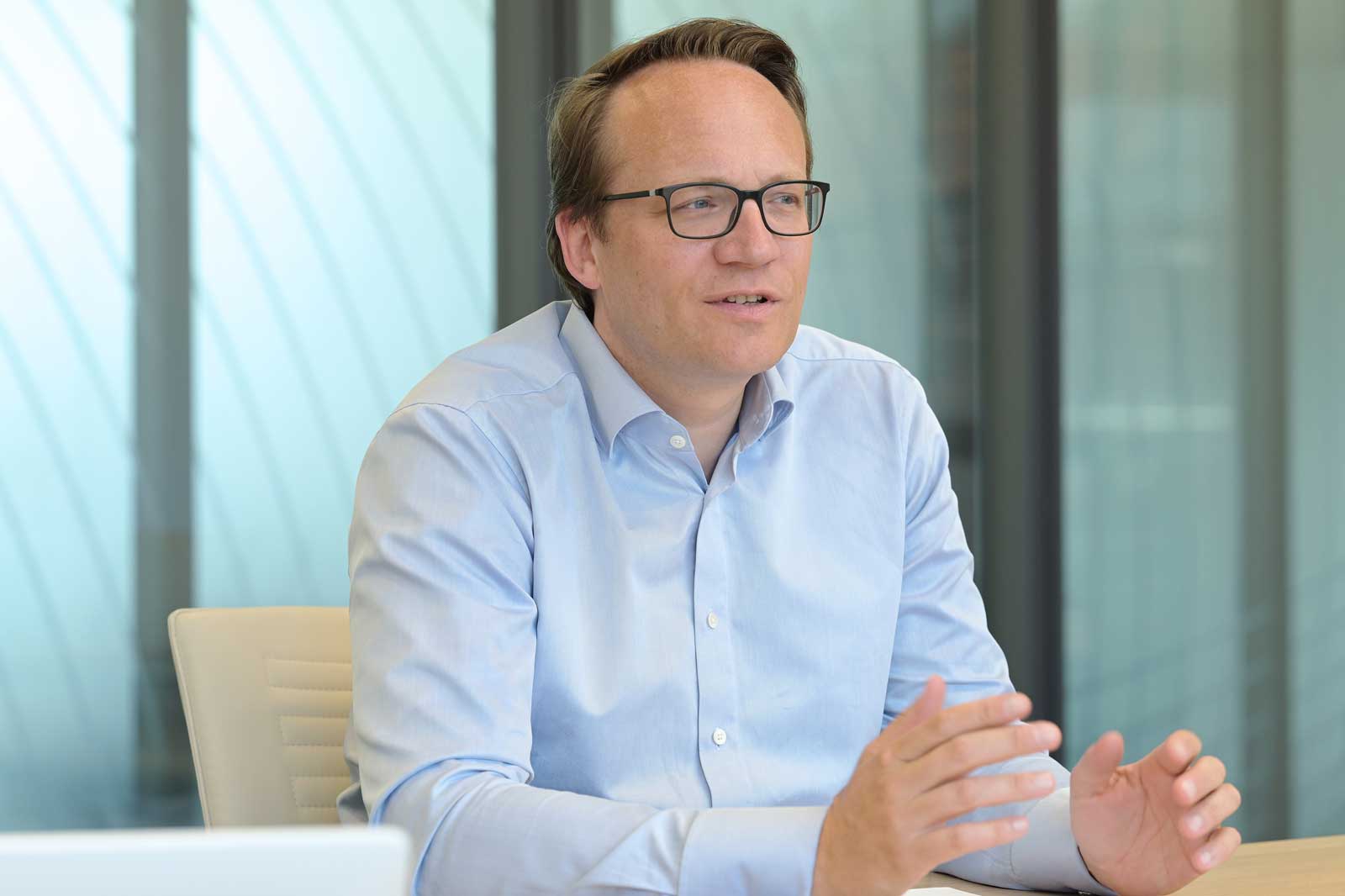 Eine Person in einem hellblauen Hemd hält eine Handbewegung während einer Besprechung in einem modernen Büroumfeld.