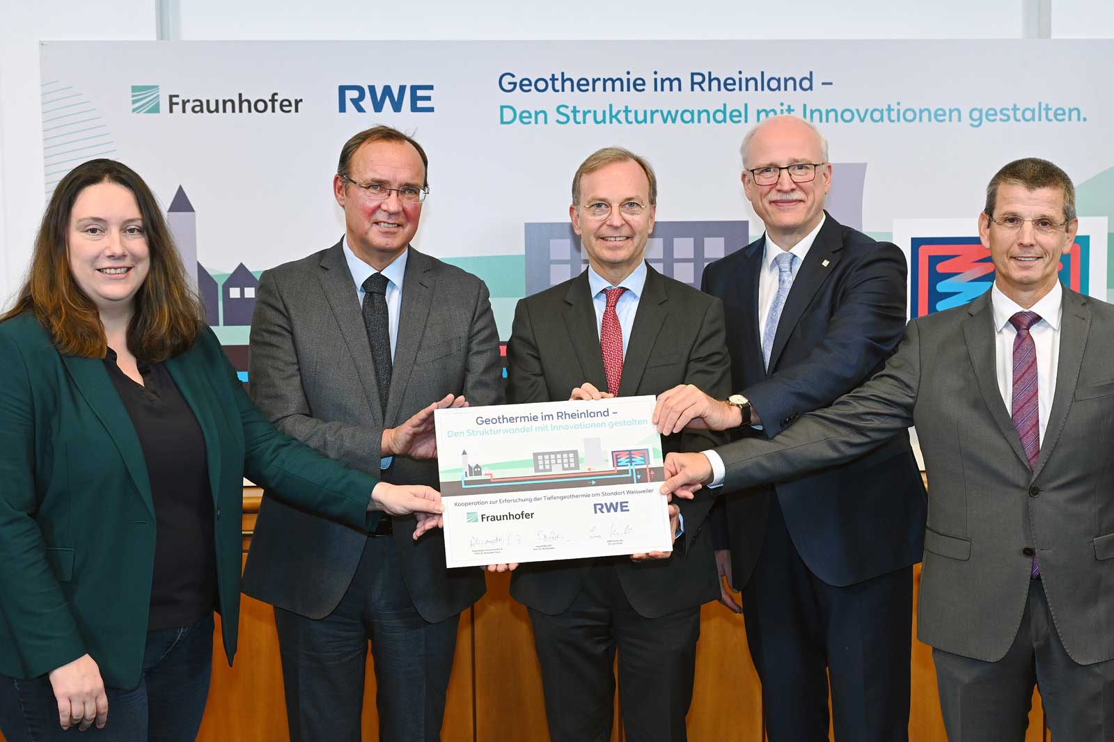 Group photo of individuals presenting a certificate for geothermal energy in the Rhineland, with a banner in the background.