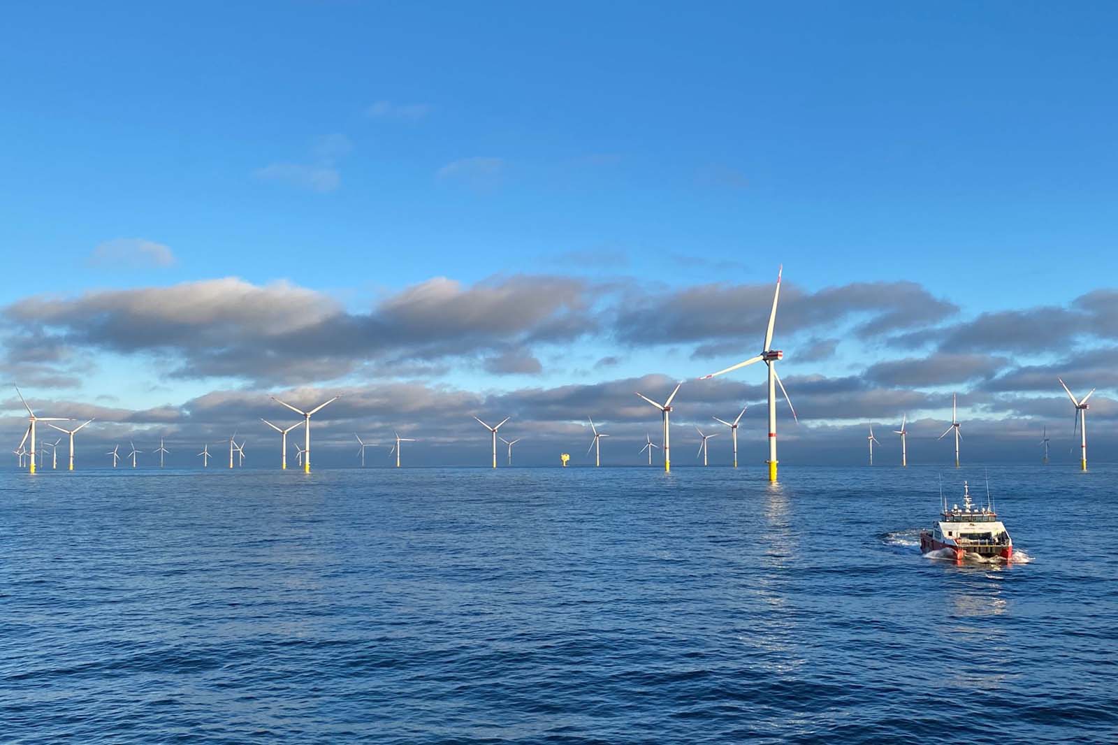 Offshore wind turbines across calm sea with service vessel