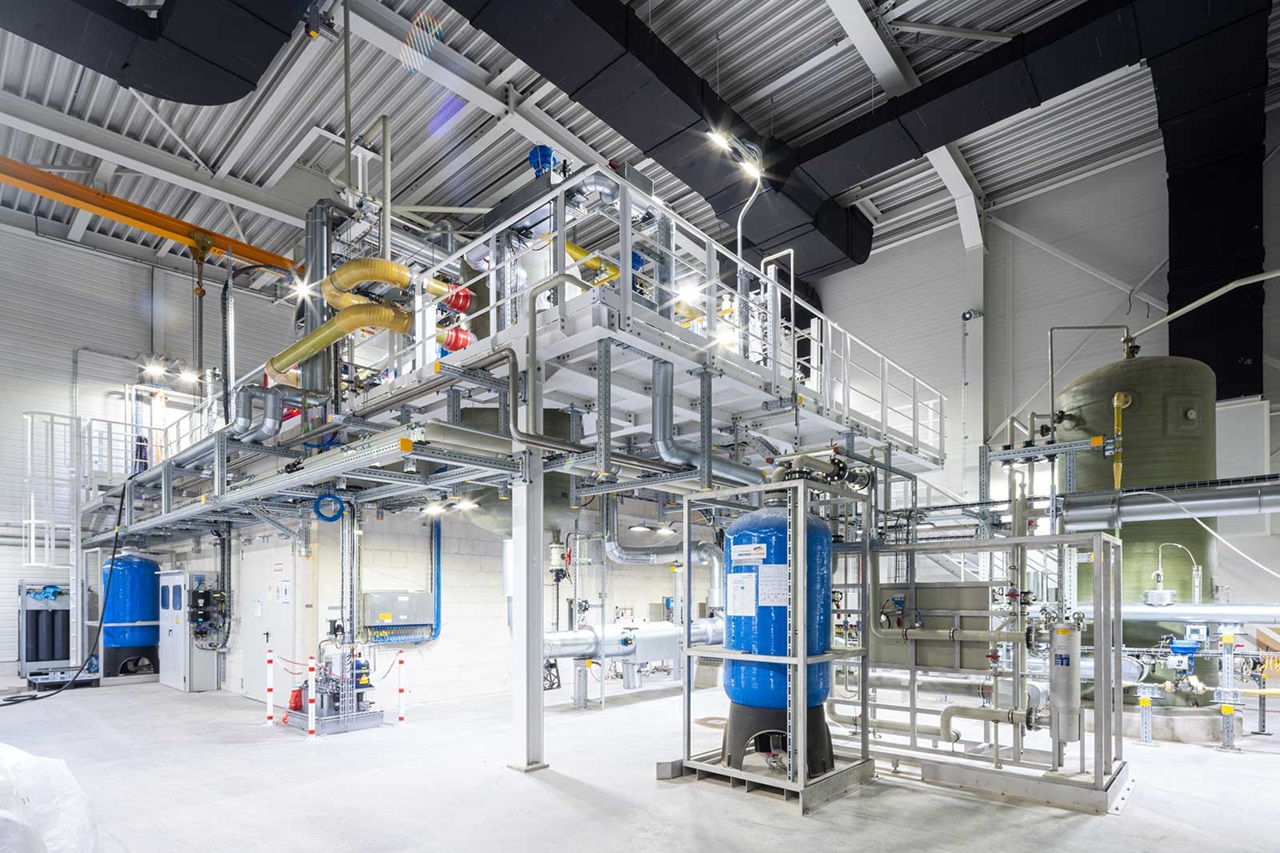 A modern industrial facility featuring pipes, tanks, and conduits within a bright, spacious environment.