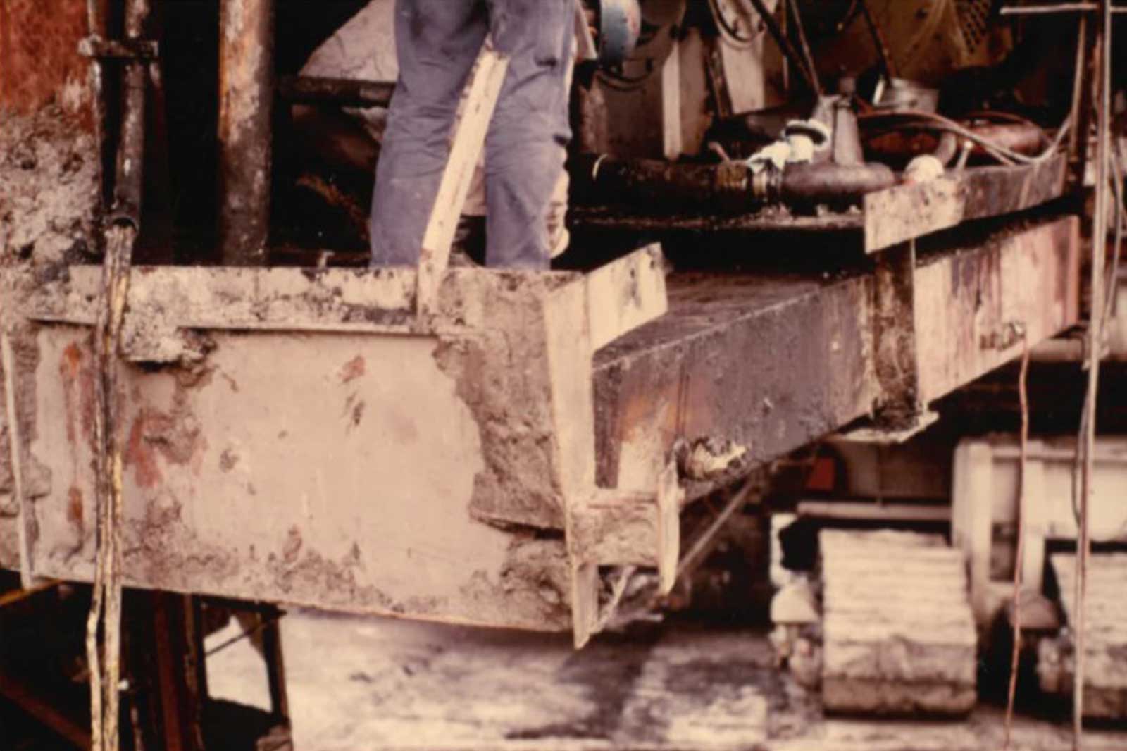 Ein großer Bagger mit einer riesigen rotierenden Trommel, die Arbeiter beim Reparieren von Maschinen an einem Bergbauort zeigt.